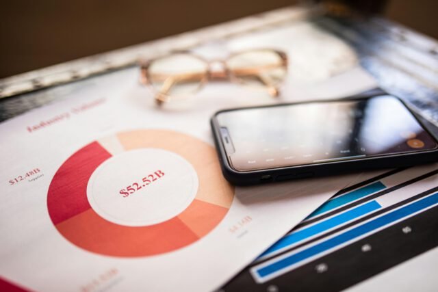A mobile phone over business charts displaying financial data for analysis.